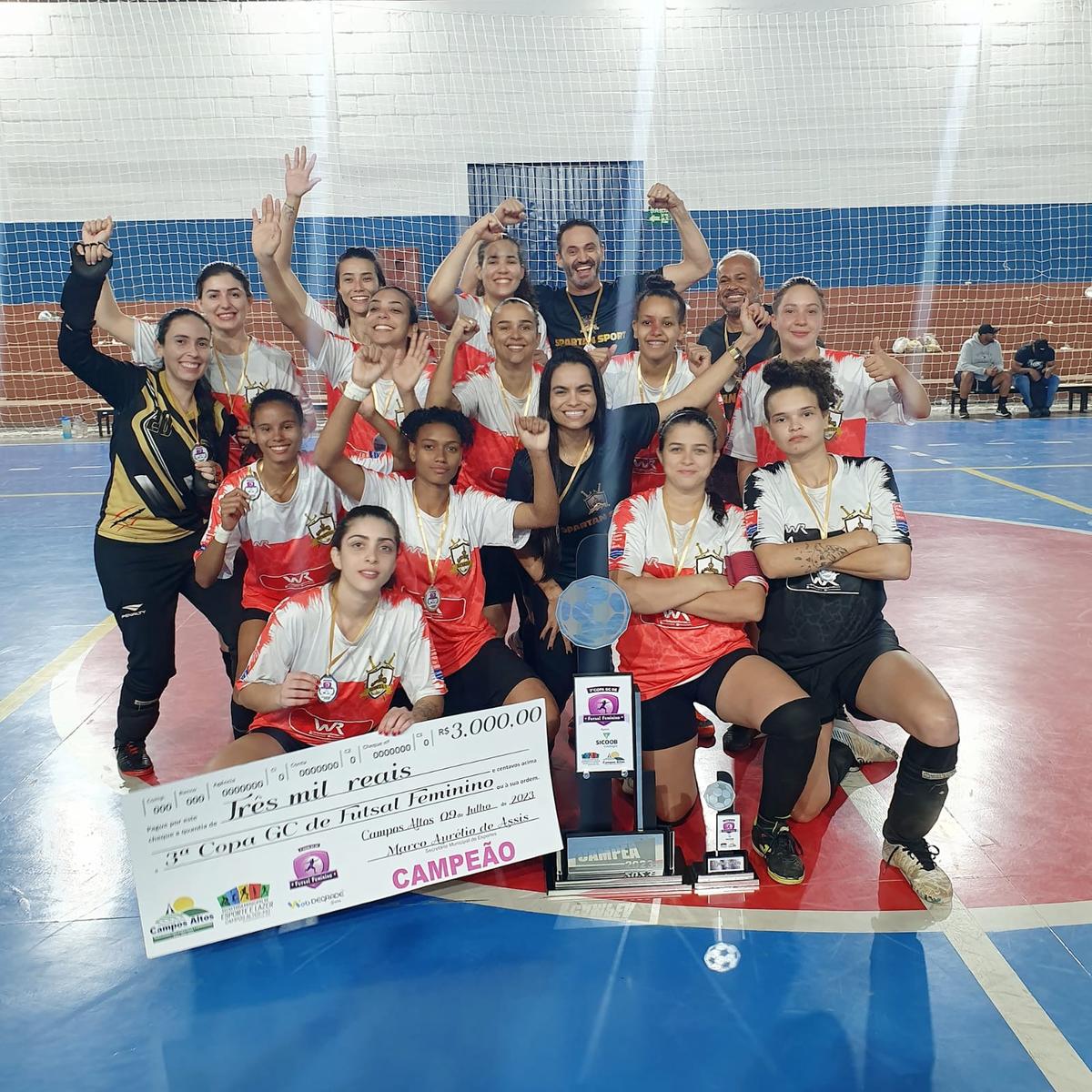 Spartan Sport com as meninas exibindo o troféu de campeãs e o cheque da premiação. (Foto/Divulgação)