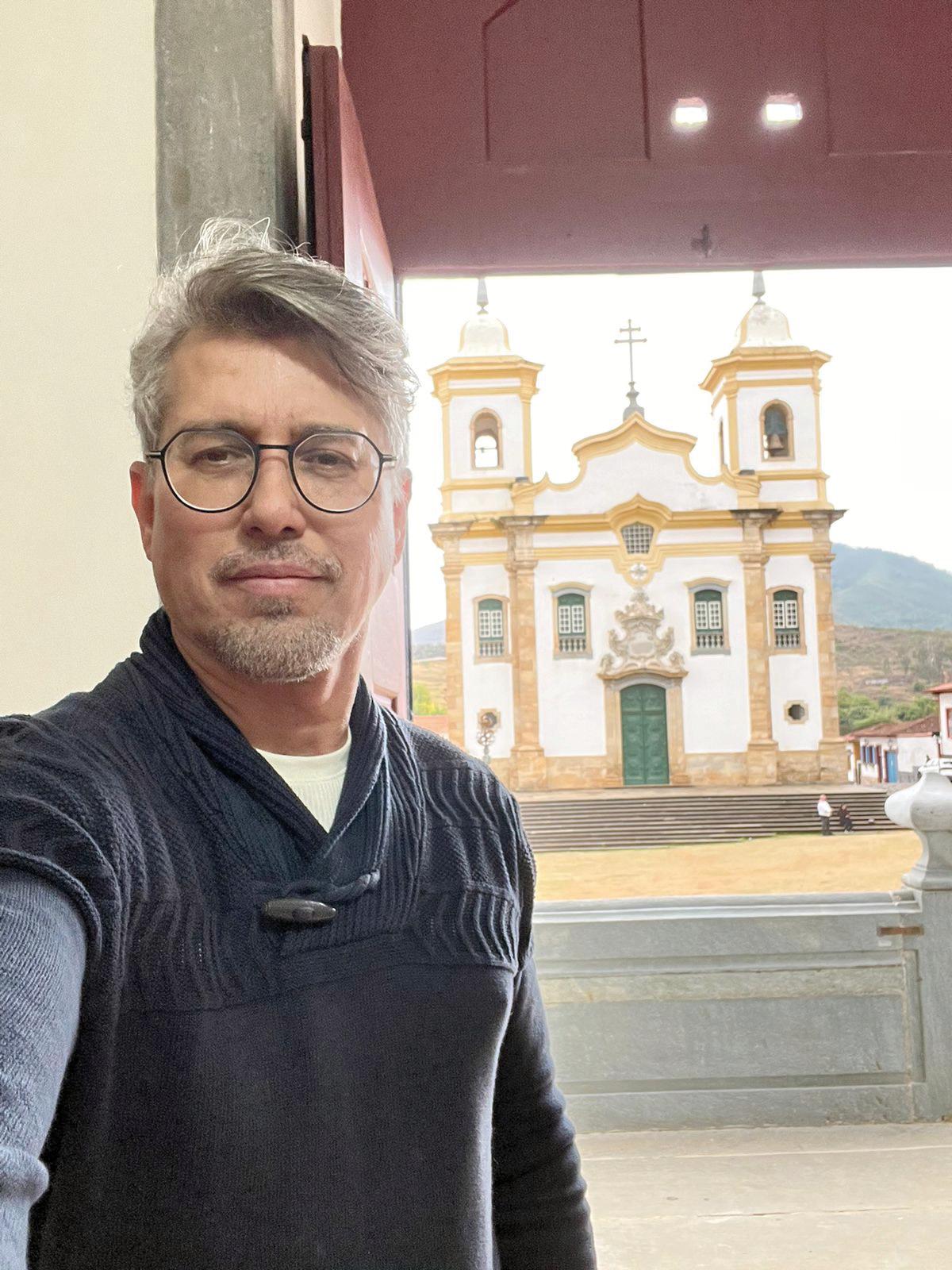 Adriano Luiz Furini,restaurador dosmais respeitados,tendo ao fundoigreja restauradapor ele, em Mariana (Foto/Divulgação)