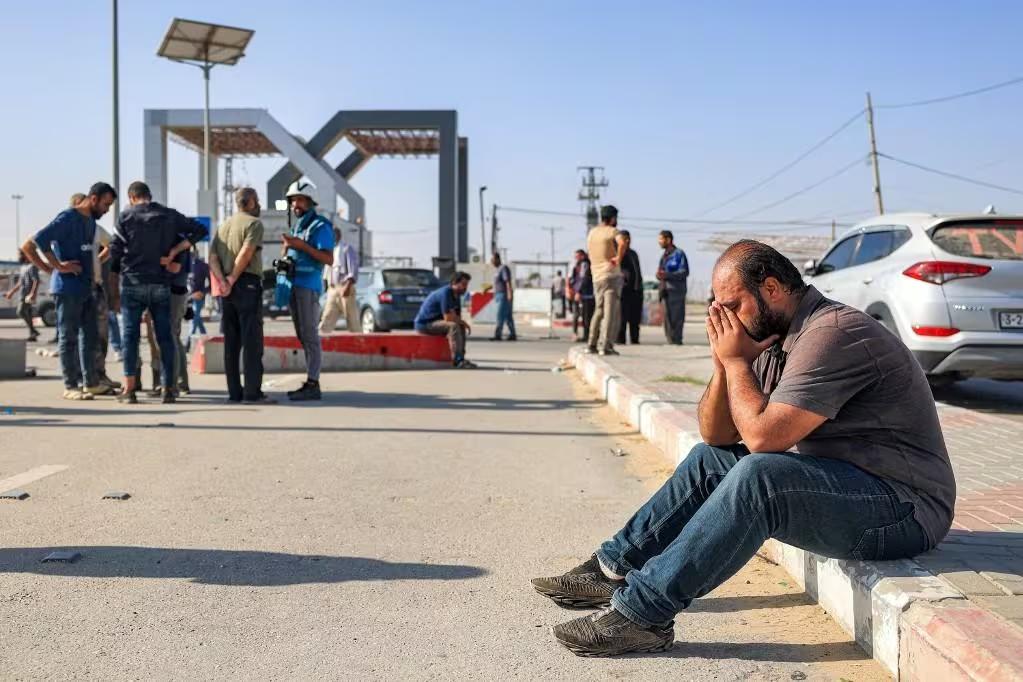 Um homem lamenta sentado perto do portão do posto fronteiriço de Rafah com o Egito, no sul da Faixa de Gaza, em 3 de novembro de 2023 (Foto/Said Khatib/AFP)