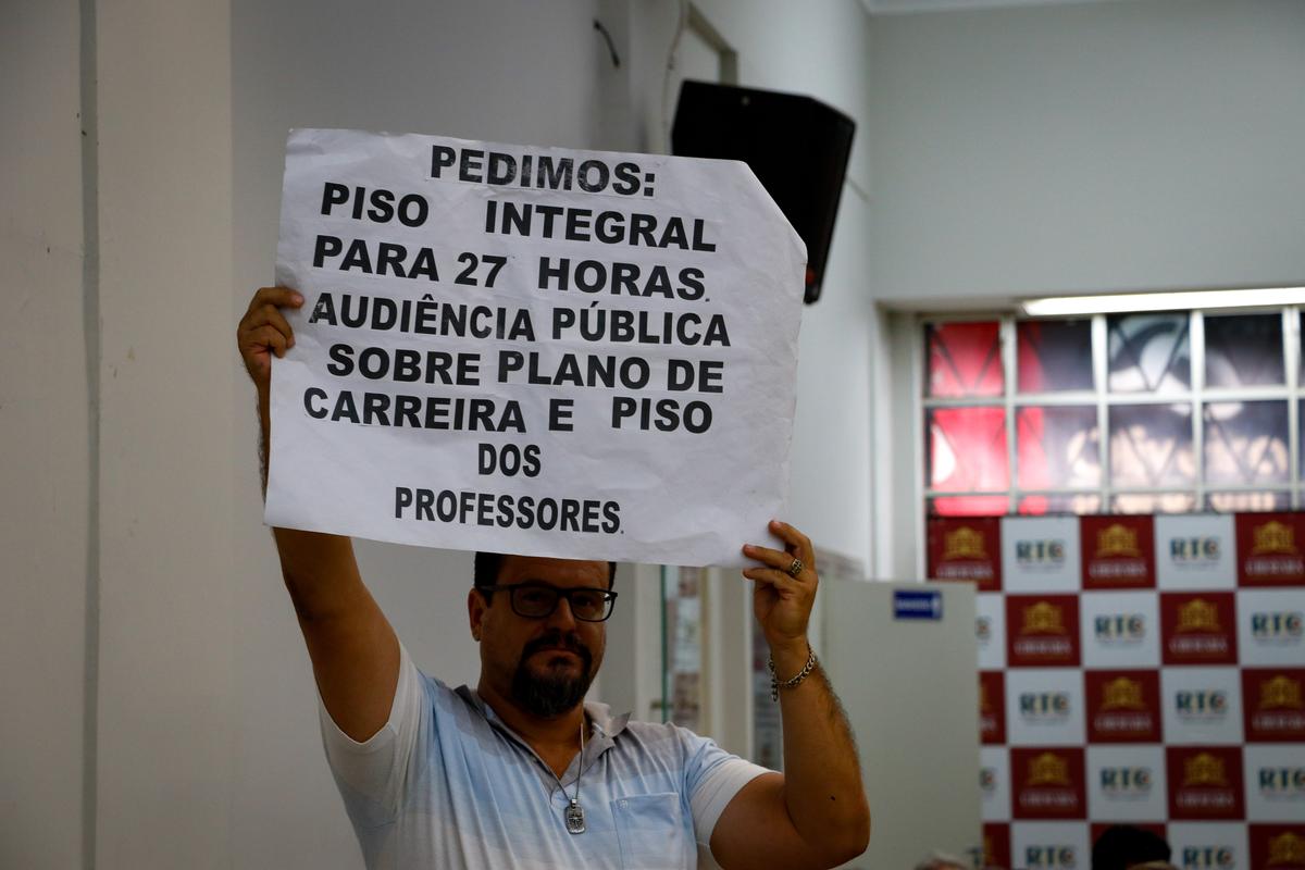 Representante de educadores, no Plenário da Câmara, mostra cartaz com as reivindicações da categoria (Foto/Rodrigo Garcia)