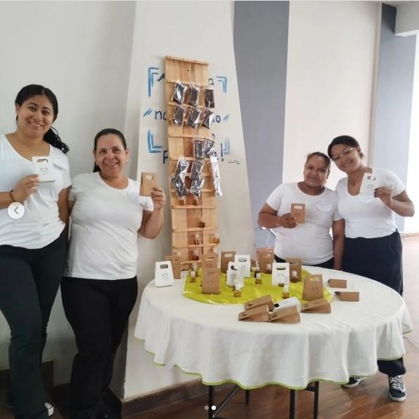 As criadoras Eliana Santana, Yasmin Bisão, Maria Luiza e Samara Aquino posam ao lado de uma prateleira com pulseiras femininas e masculinas penduradas. (Foto/Reprodução)