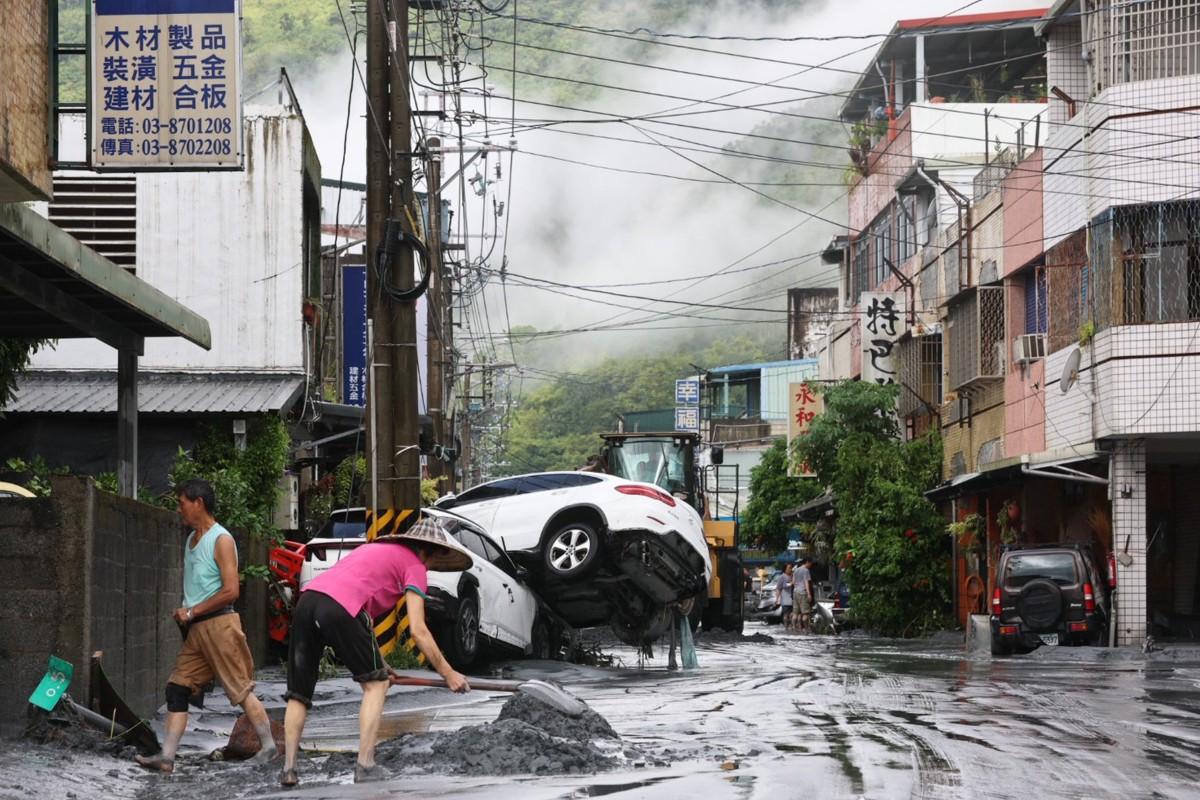 Moradores limpam a lama de suas propriedades, enquanto carros danificados são vistos ao fundo, em Hualien, Taiwan (Foto/Johnson LIU/AFP)
