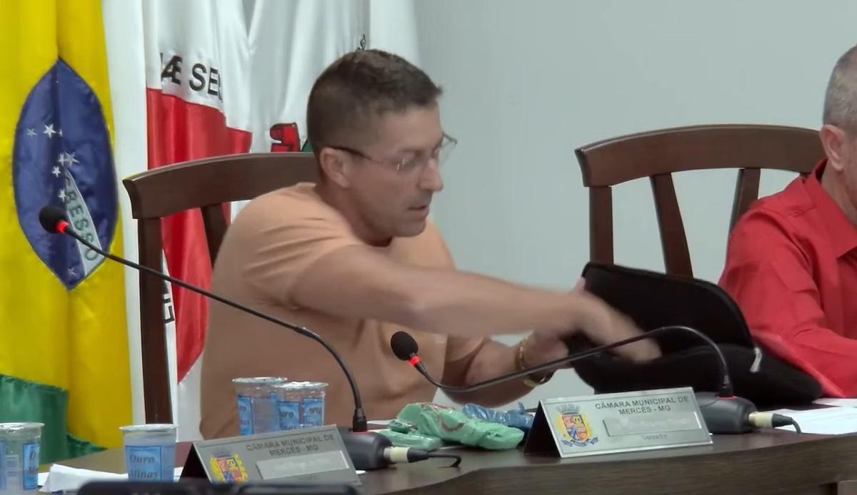 No momento de registrar o voto, Marcelo Moto Som tirou uma grande quantidade de dinheiro de uma bolsa e colocou sobre a mesa (Foto/Reprodução/YouTube/Câmara Municipal de Mercês)
